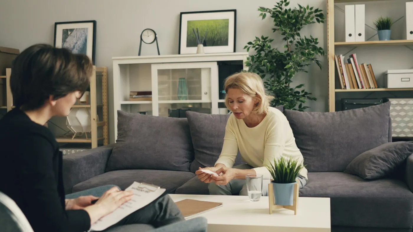 A woman sitting on a couch talking to another woman